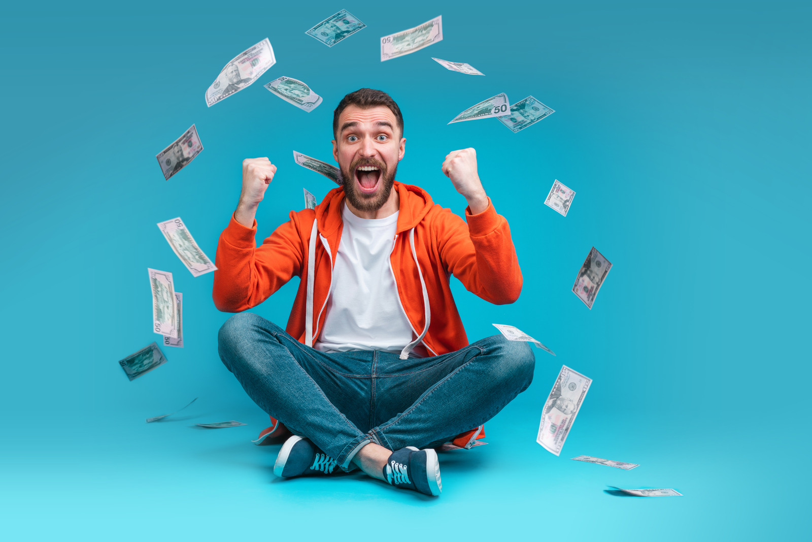 Bearded man showing sincere excitement about his favorite team victory. Guy being happy winning a bet online at bookmaker's website. Dollar banknotes rain falling down.